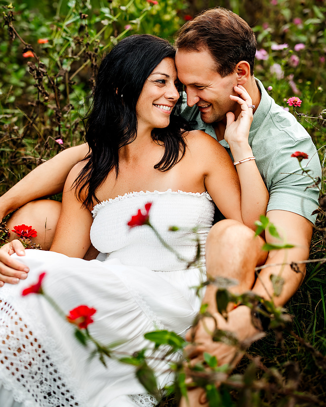 A couple sitting in wildflowers, laughing together
