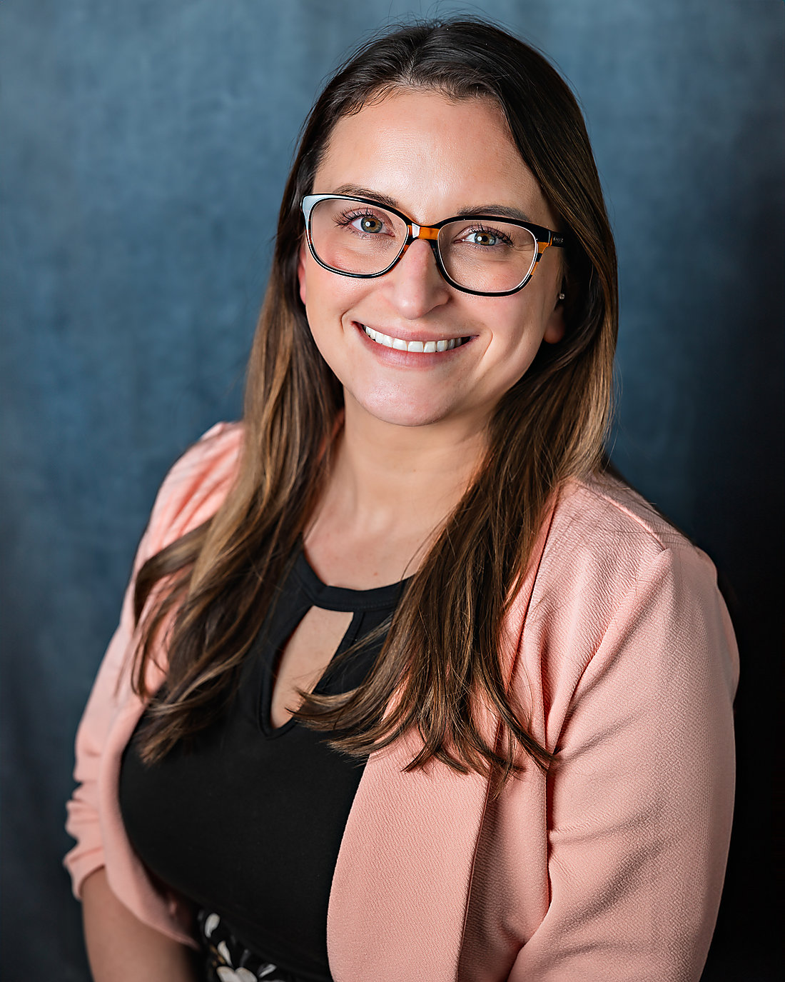 A professional headshot on a blue backdrop
