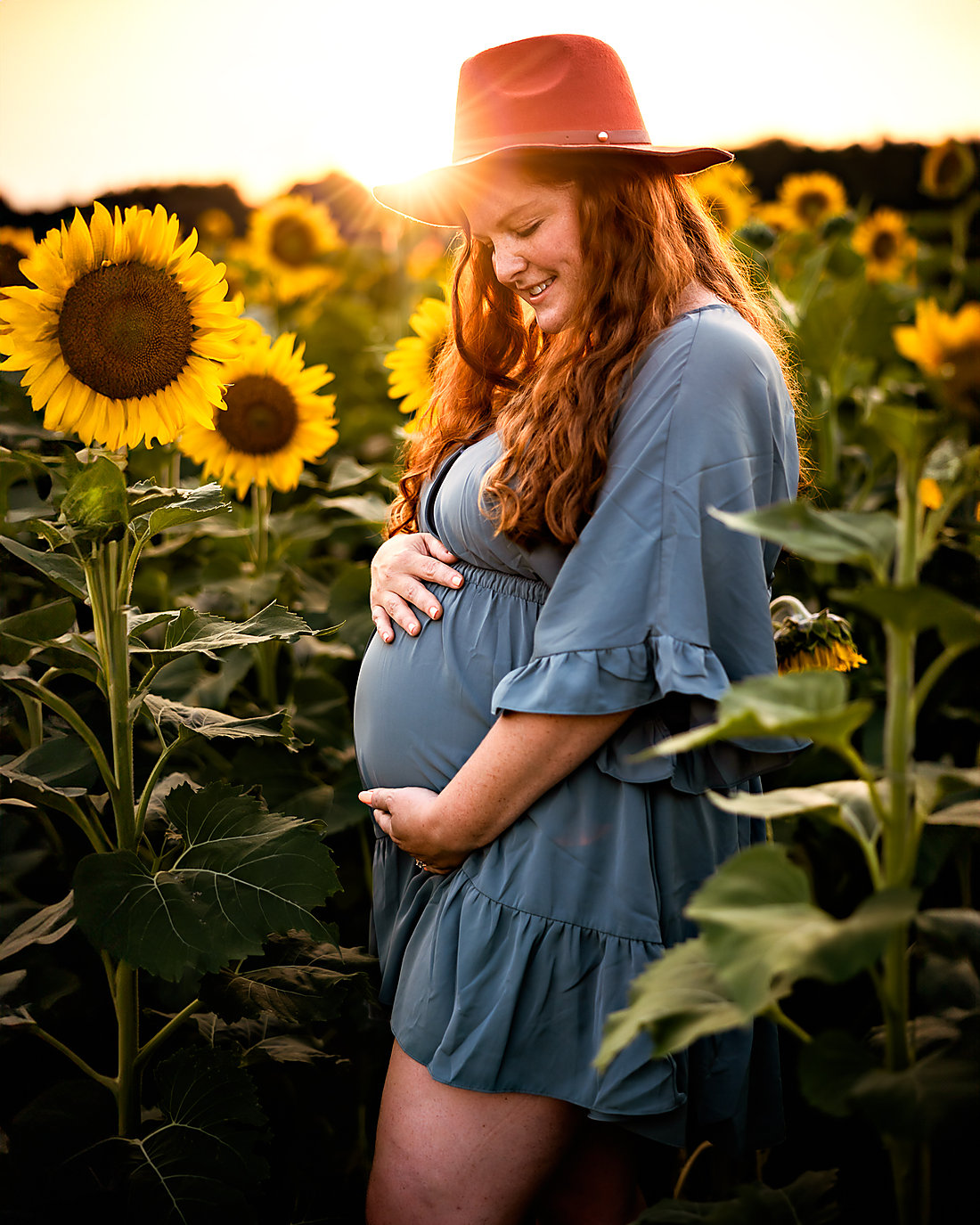 A mother-to-be among sunflowers at sunset