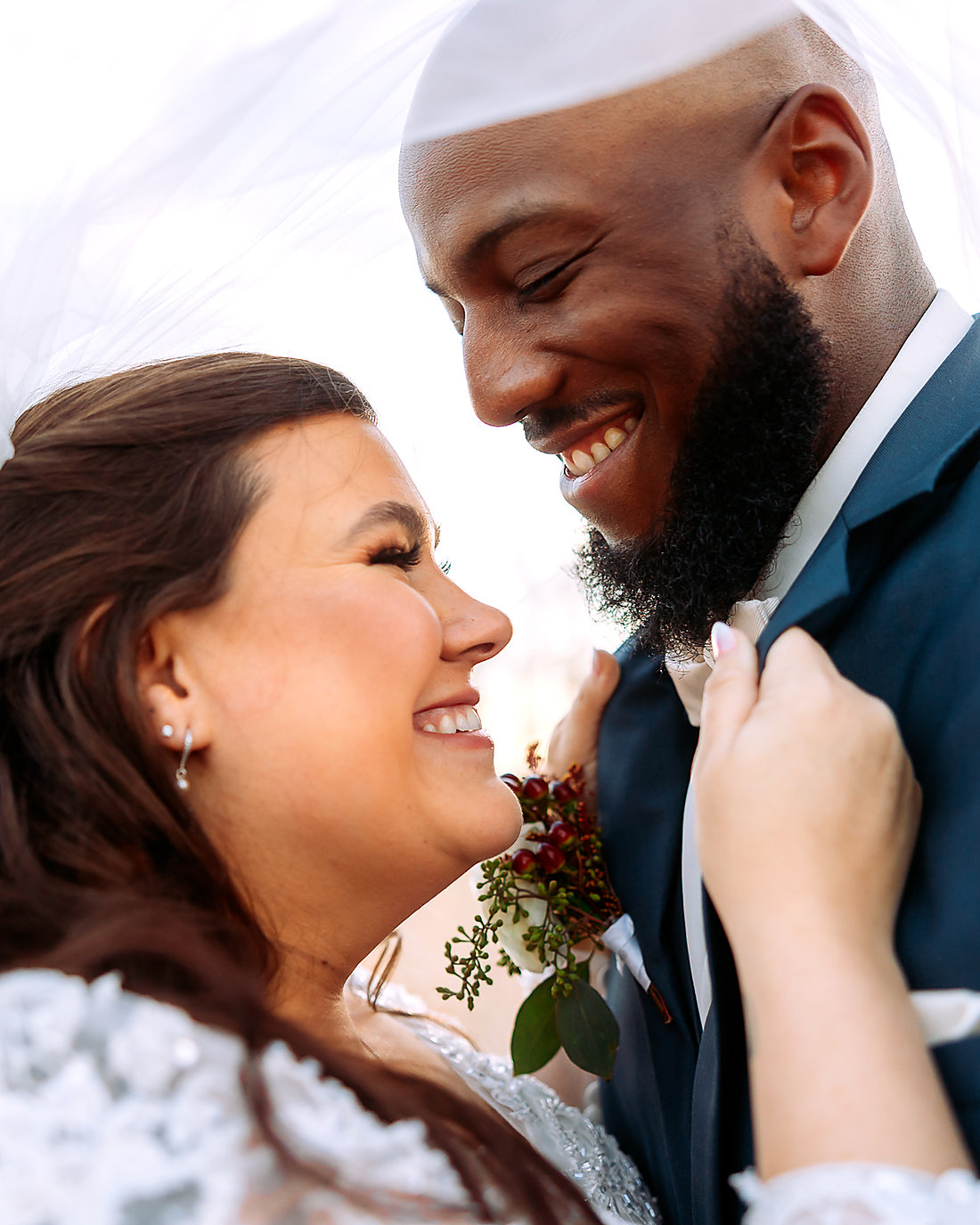 A bride and groom laughing under her veil